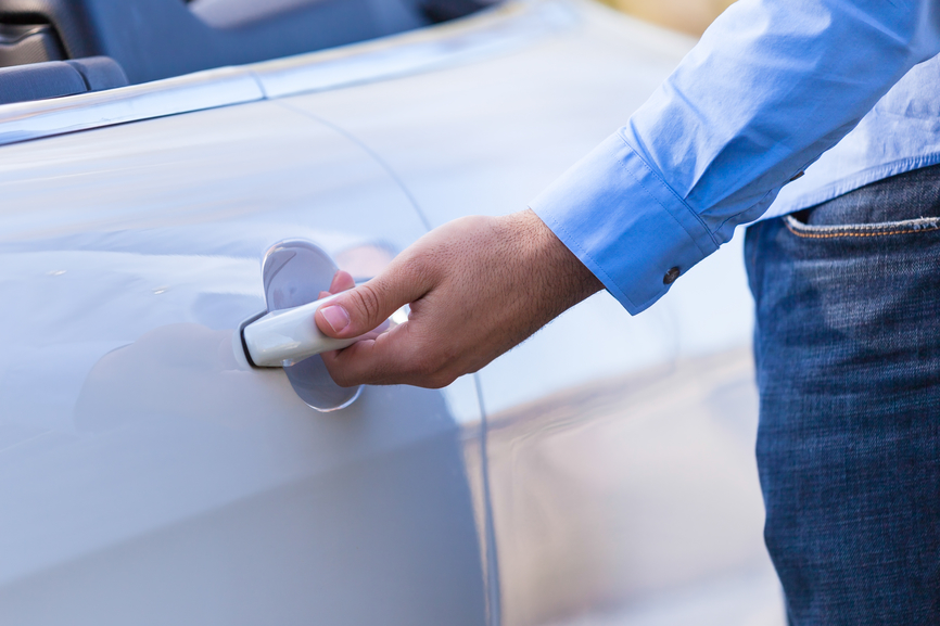 Young latin american driver opening his new car door