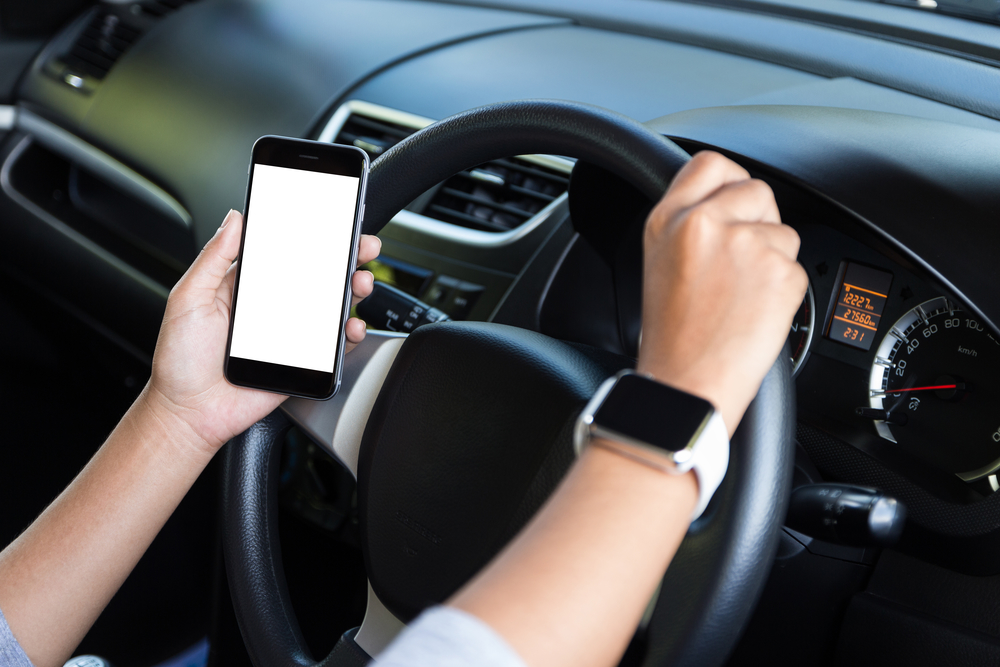 hand holding phone white screen and driving car