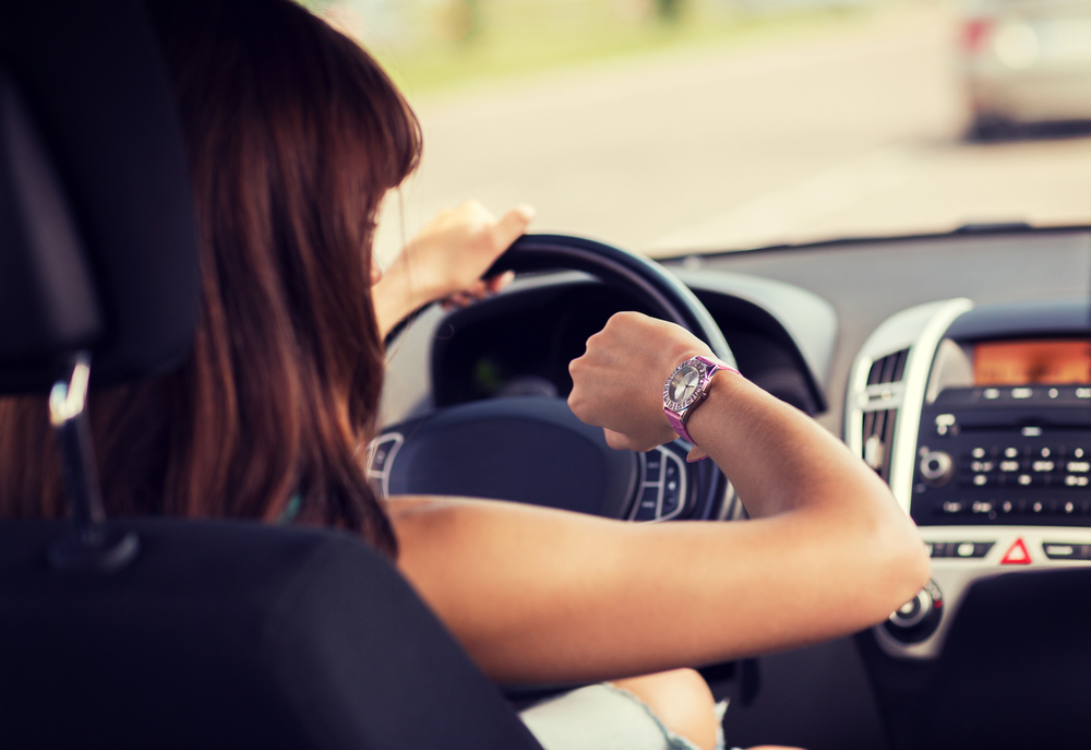 woman driving a car and looking at watch