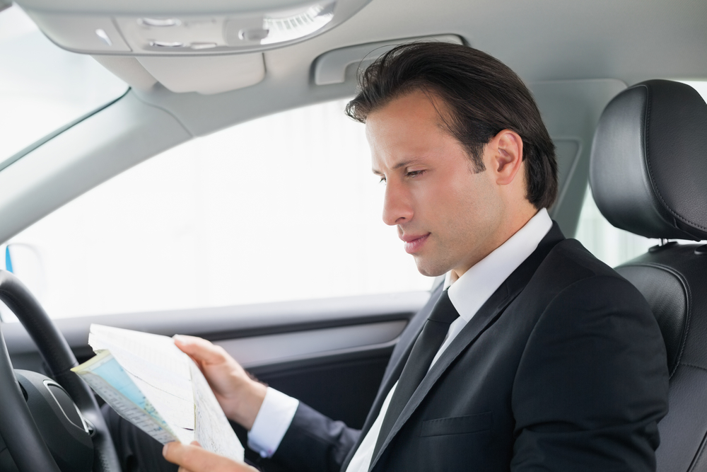 Businessman reading a map in his car