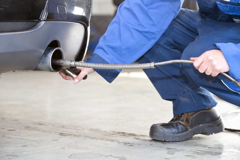 Mechanic, checking the exhaust fumes of a diesel fuelled passenger car for emission gasses, such as carbon dioxide.