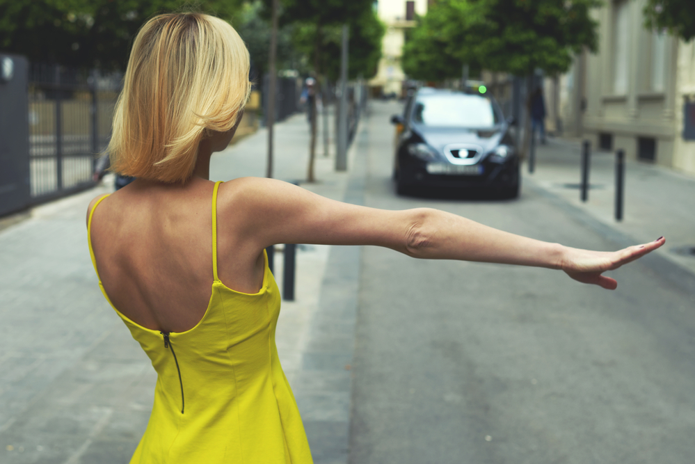 woman in yellow dress hailing a car cab taxi.