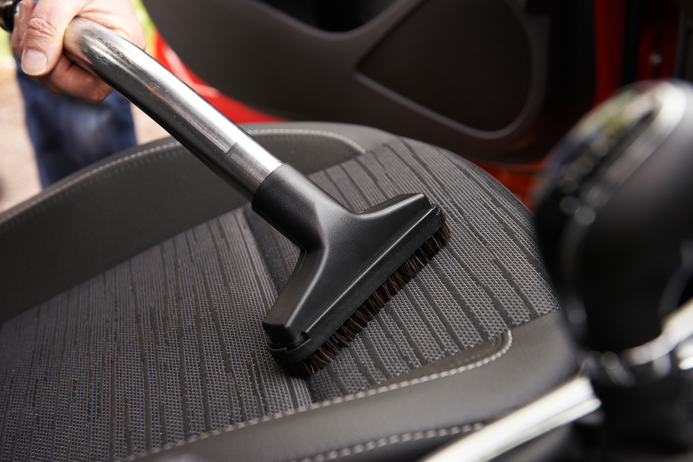 Man Hoovering Seat Of Car During Car Cleaning