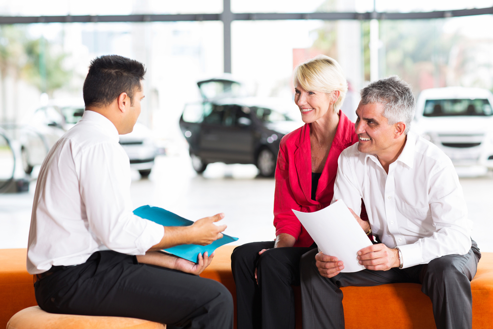 vehicle salesman explaining contract to senior couple