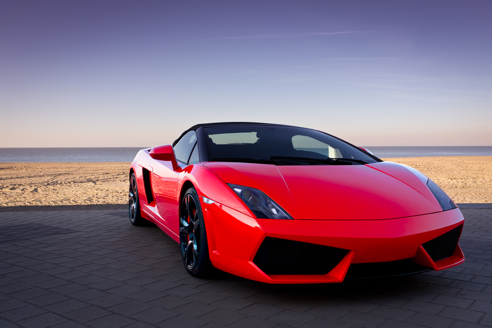 Red sports car at sunset beach