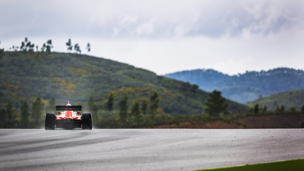 Motorsport driver drives in the rain in a beautifull landscape of hills. with the spray of rain behind the car.