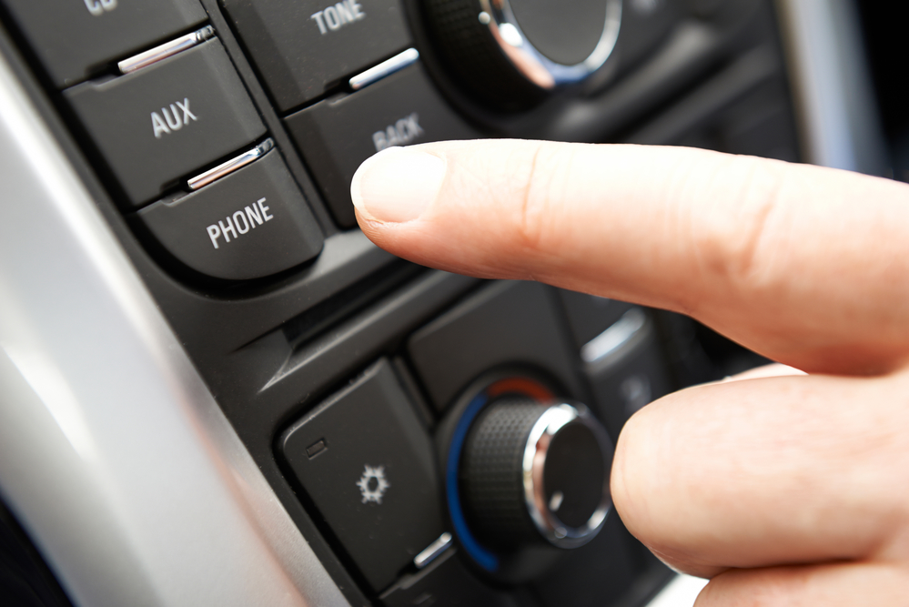 Close Up Of Hand Pressing Car Bluetooth Control On Dashboard