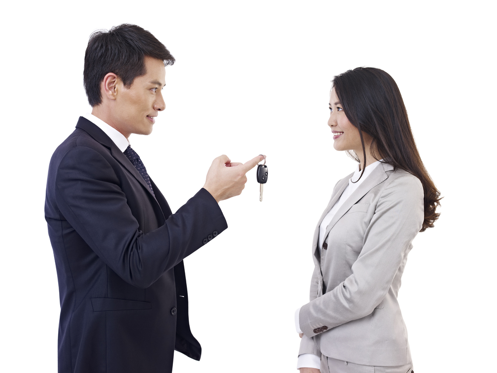 man handing car key to woman