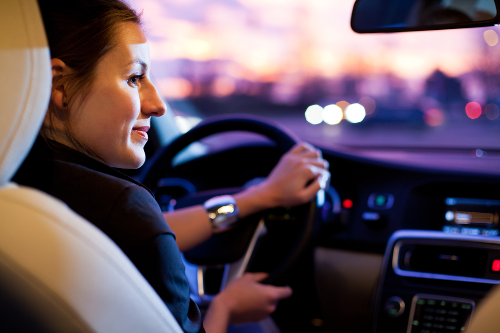 Driving a car at night - pretty, young woman driving her modern