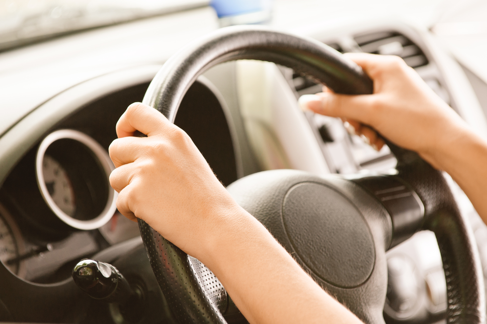 Wheel of car from hand of driver. Hands at two and ten.