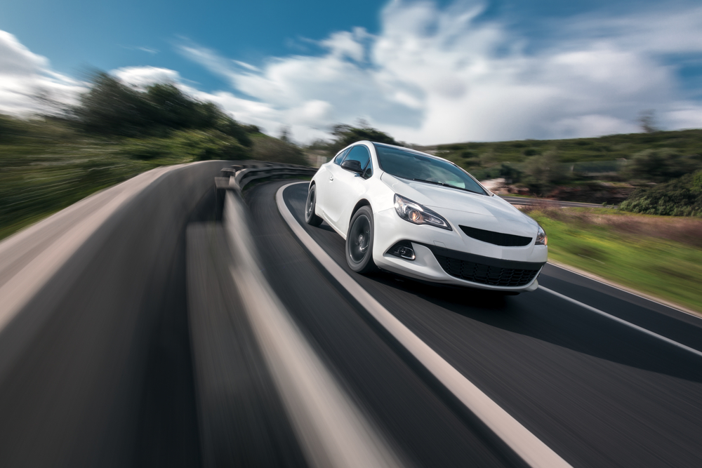 White car cornering in mountain road with speed blur