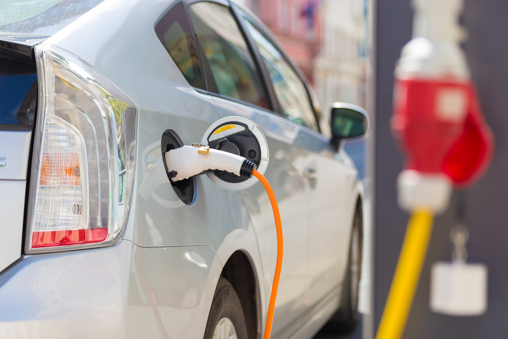 ower supply for electric car charging. Electric car charging station. Close up of the power supply plugged into an electric car being charged.