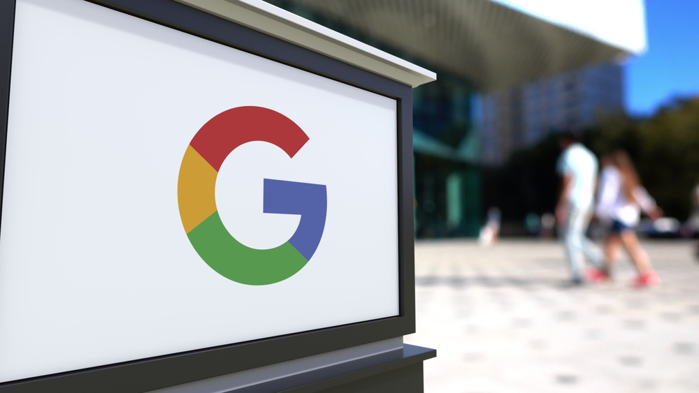 Letrero callejero con el logotipo de Google. Fondo borroso con un centro de oficinas y gente caminando. Renderizado 3D editorial, Estados Unidos.