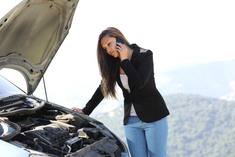 Woman on the phone looking her crash breakdown car in a road in the middle of the mountain