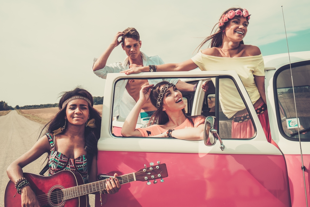 Multi-ethnic hippie friends with guitar on a road trip