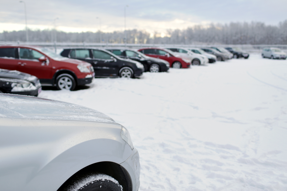 transportation, winter and vehicle concept - car parking with snow