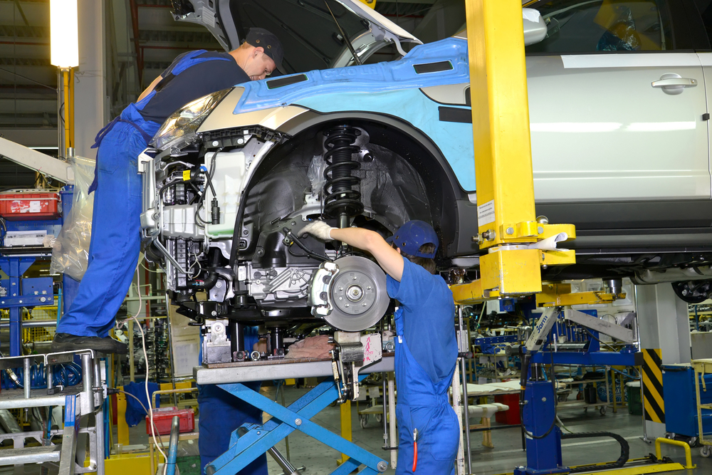 Workers install the engine on the car. Assembly conveyor of automobile plant