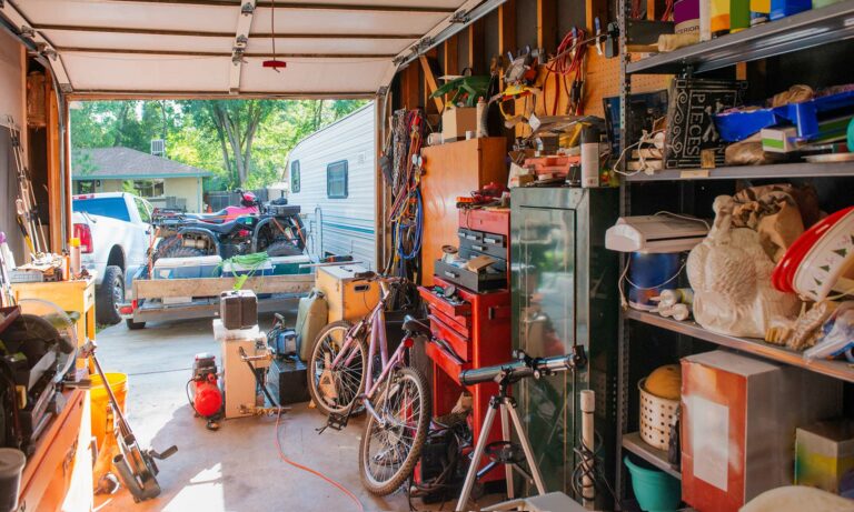 The inside of a family's garage that is filled with miscellaneous boxes, tools and other items.