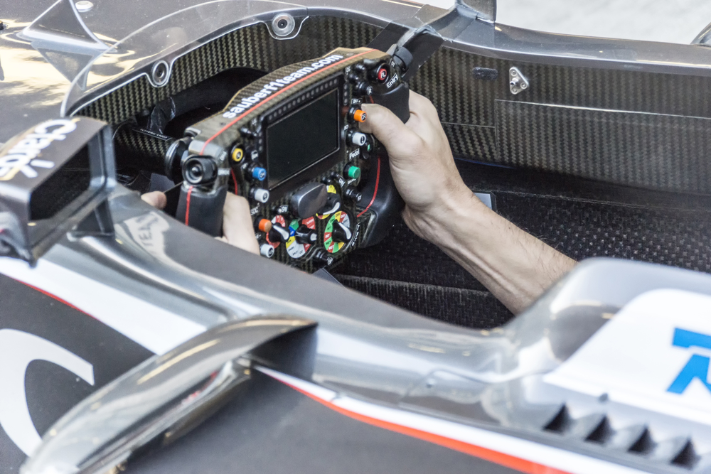 The mechanic in the cockpit of the car. Hands on the wheel.