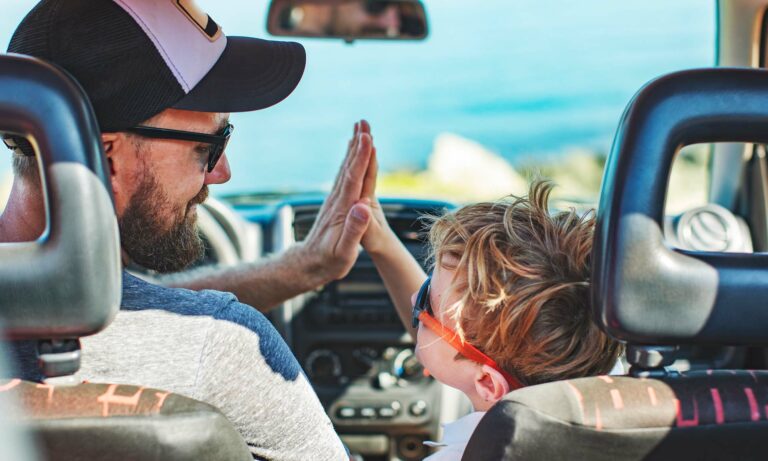 A father and son high-fiving each other in their car.