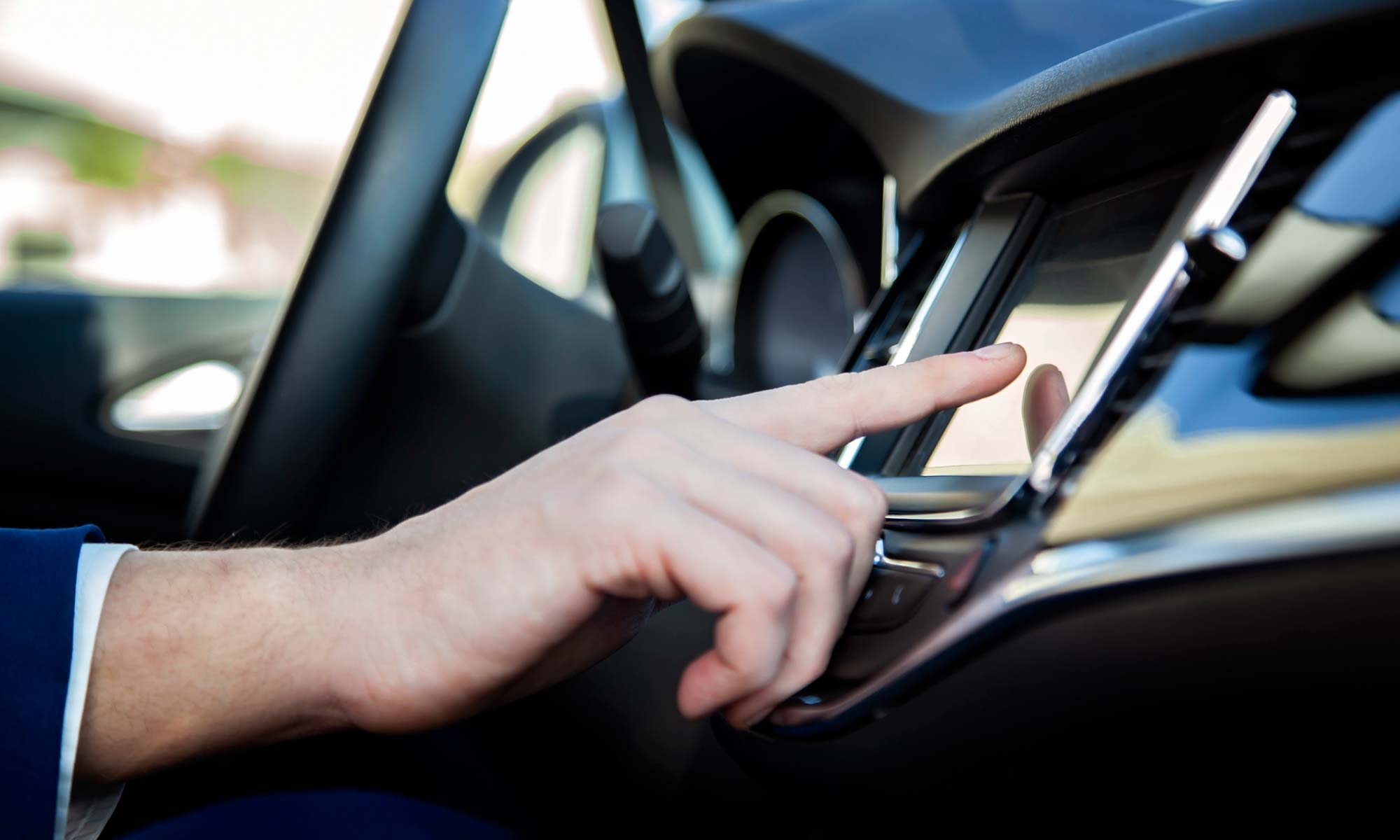 A man touching the infotainment display on his car's dashboard.