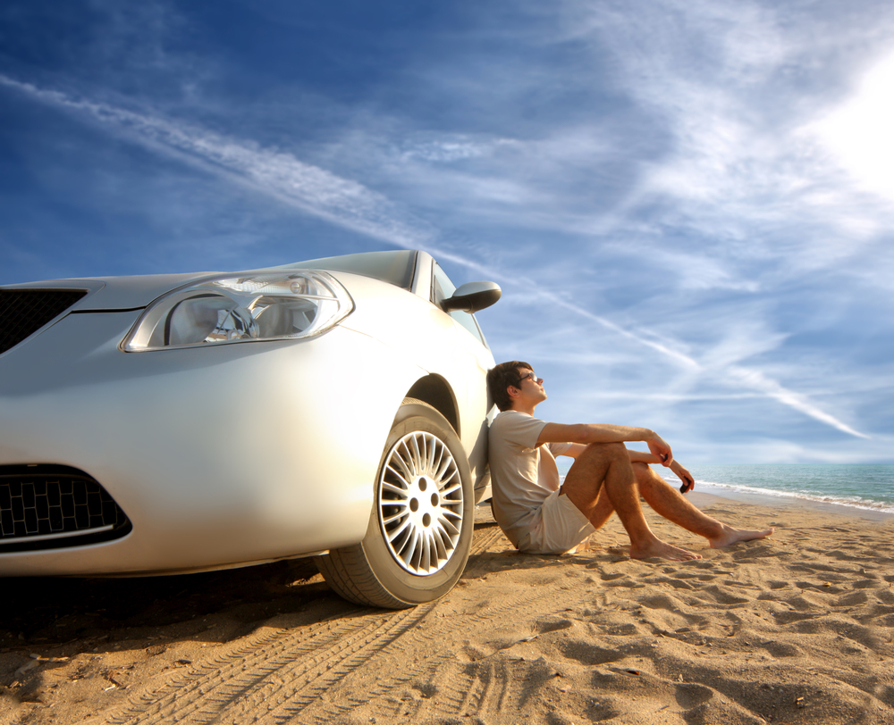 Person sitting on ground leaning on white car