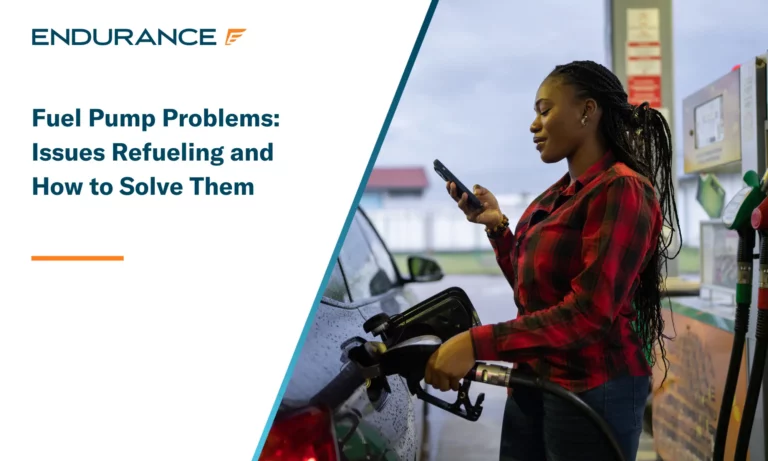 Woman at the gas station pumping fuel and looking at her mobile phone