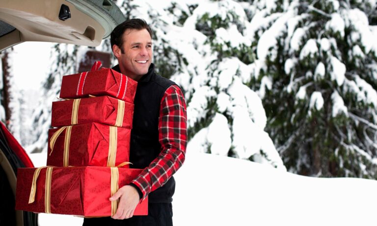 A man loads his car's trunk with holiday gifts.