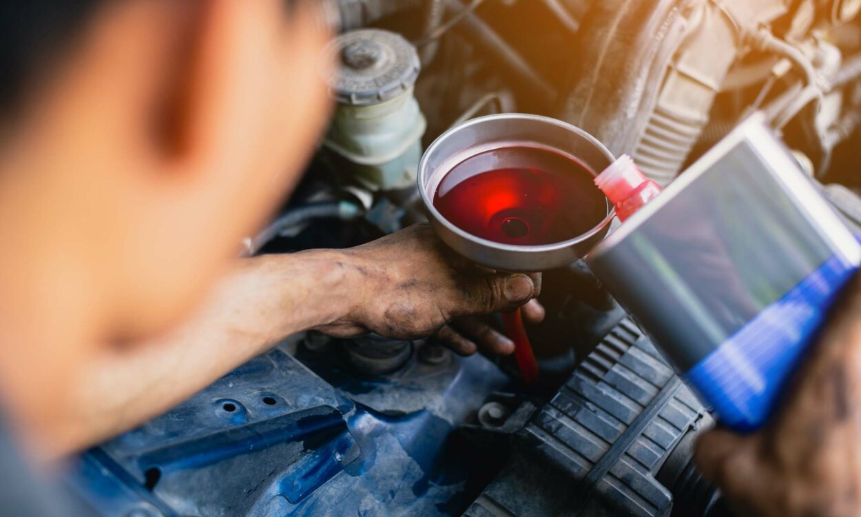 A man refilling his transmission fluid in car.