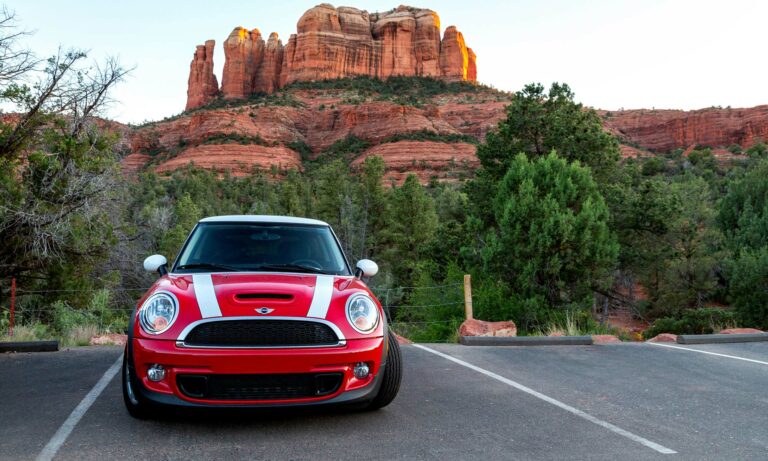 A red Mini Cooper parked in the desert.