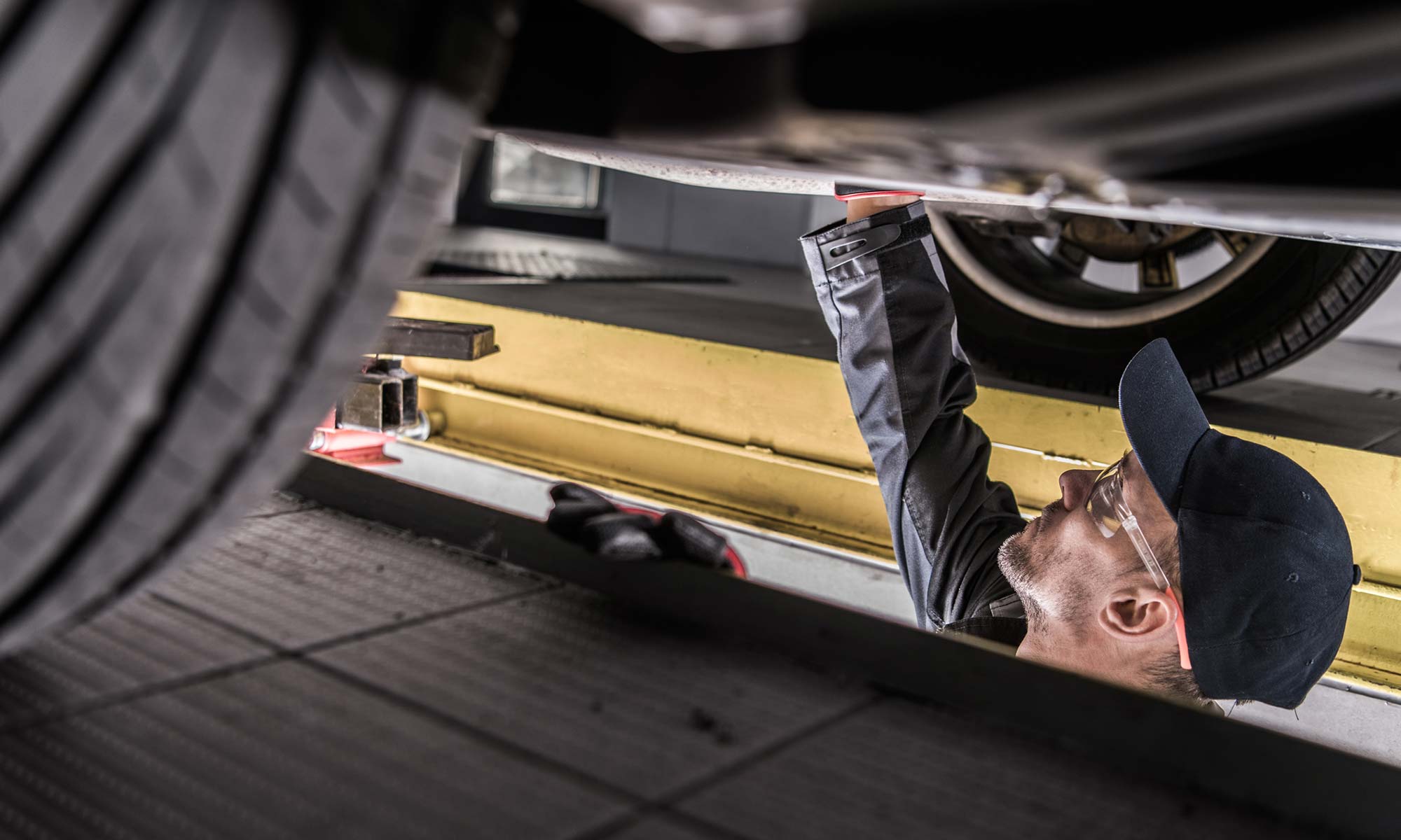 A male mechanic checks the drivetrain of a vehicle.