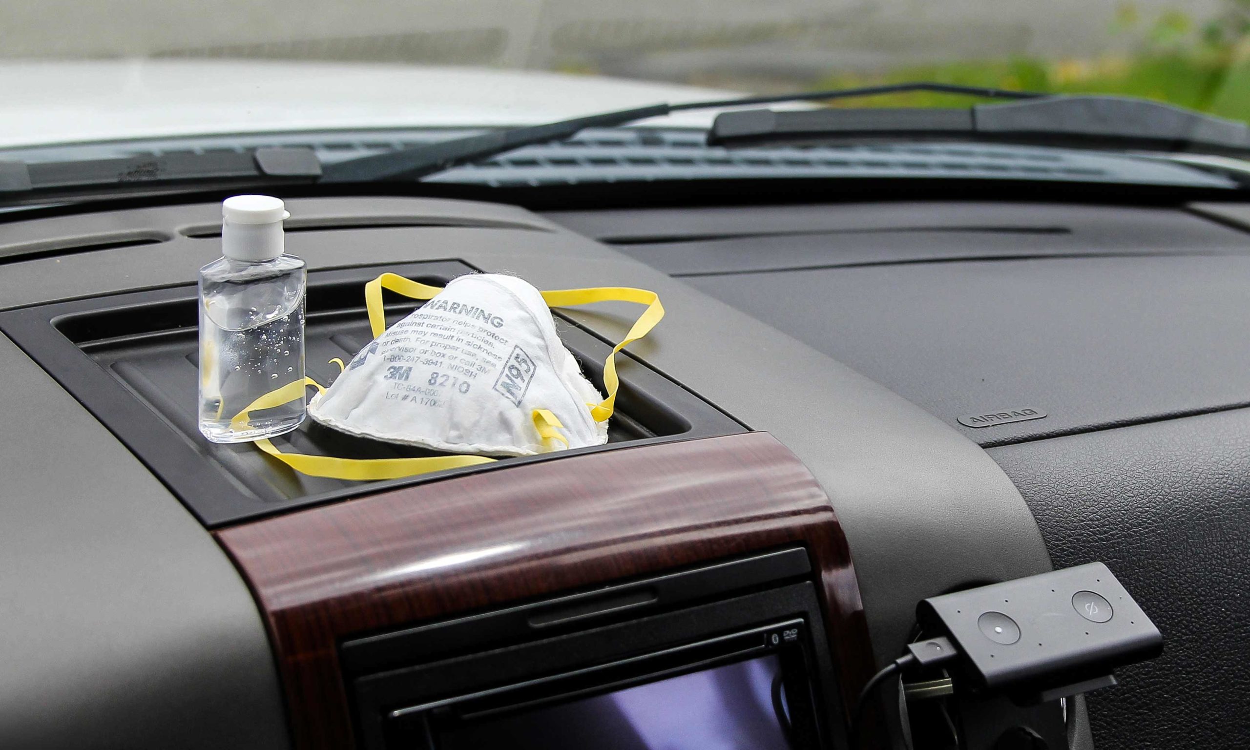 N95 mask and hand sanitizer on cars dashboard