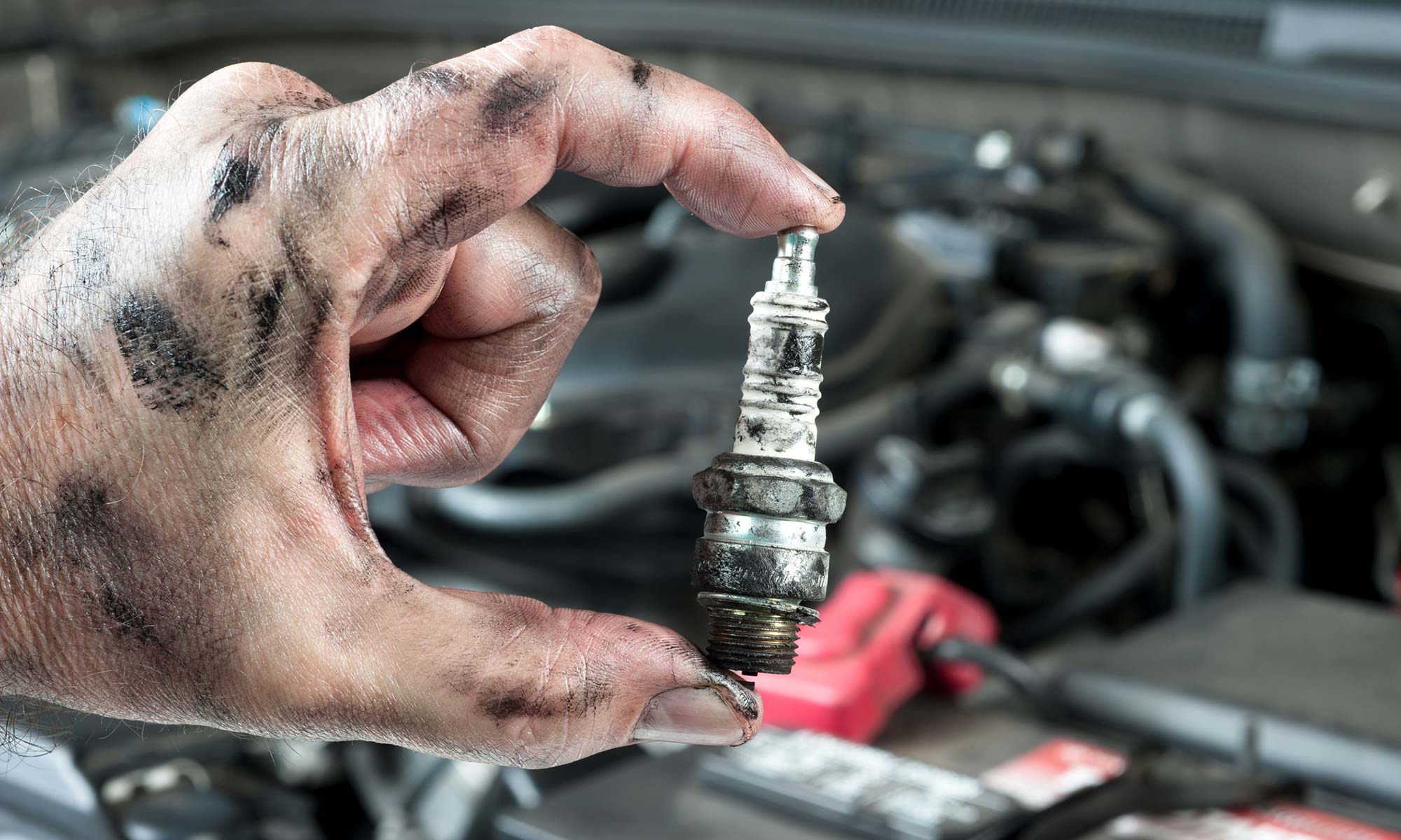 A person holding up an old spark plug for a vehicle.