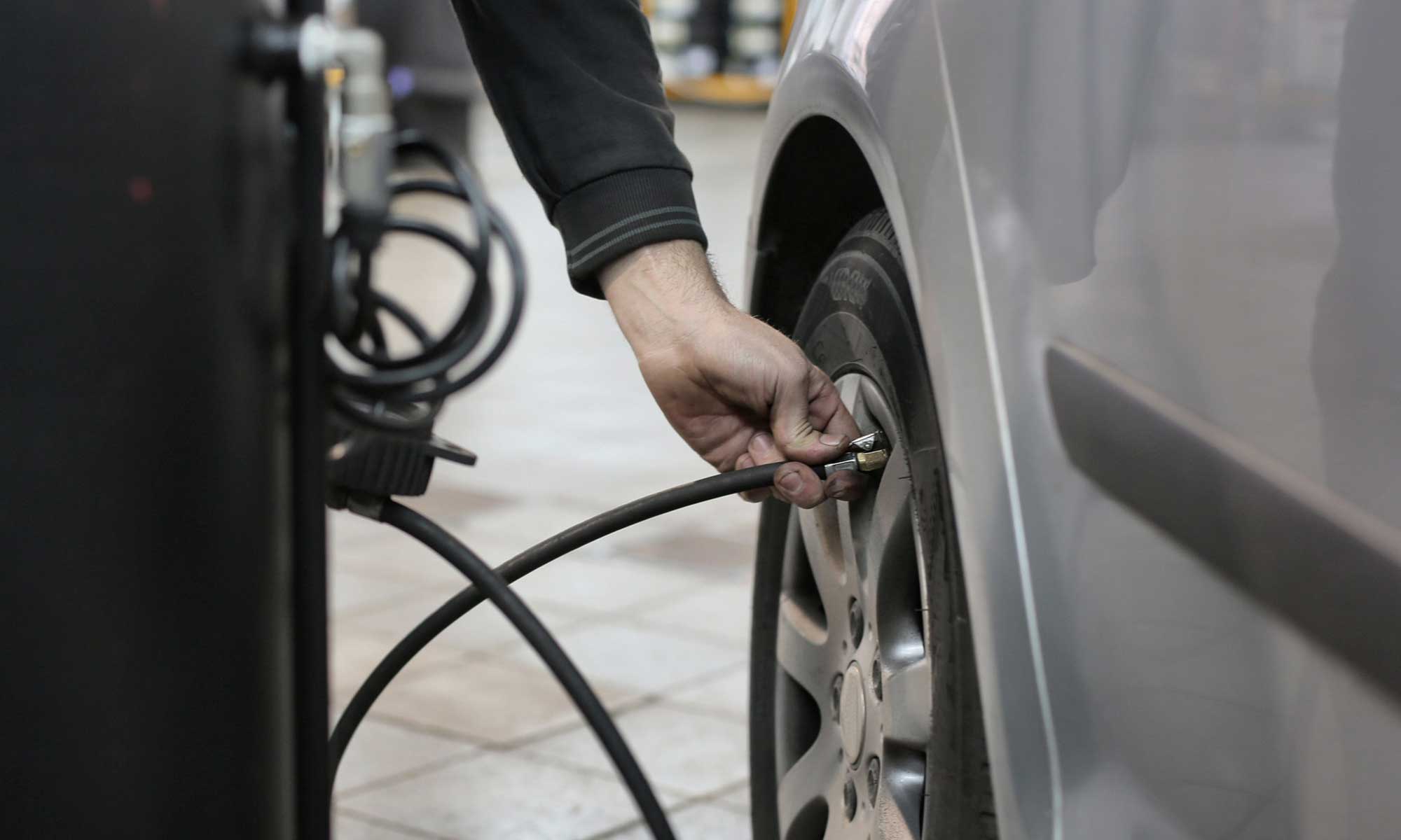 A man fills his car tire with air at an air pump.