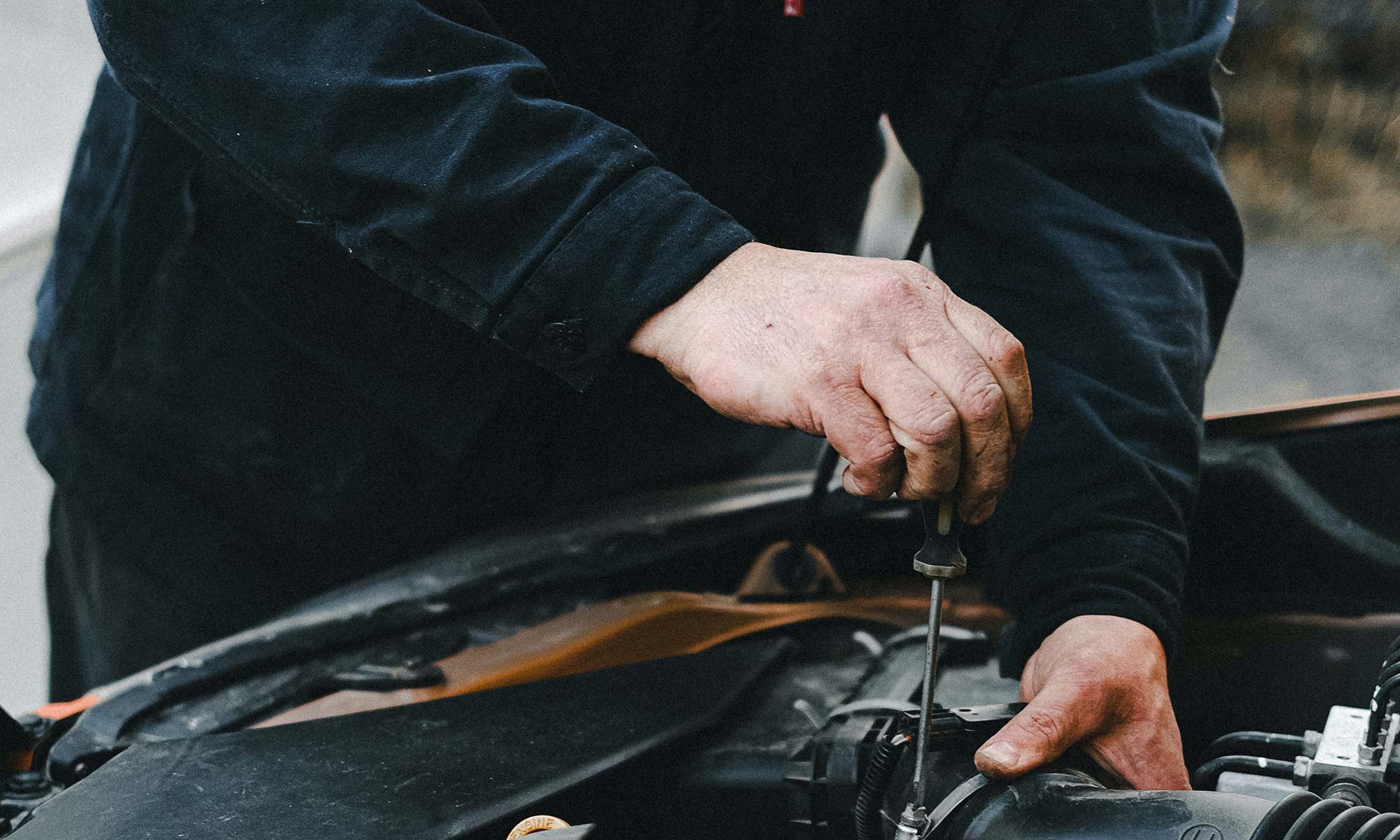 A mechanic repairing part of a vehicle's engine.