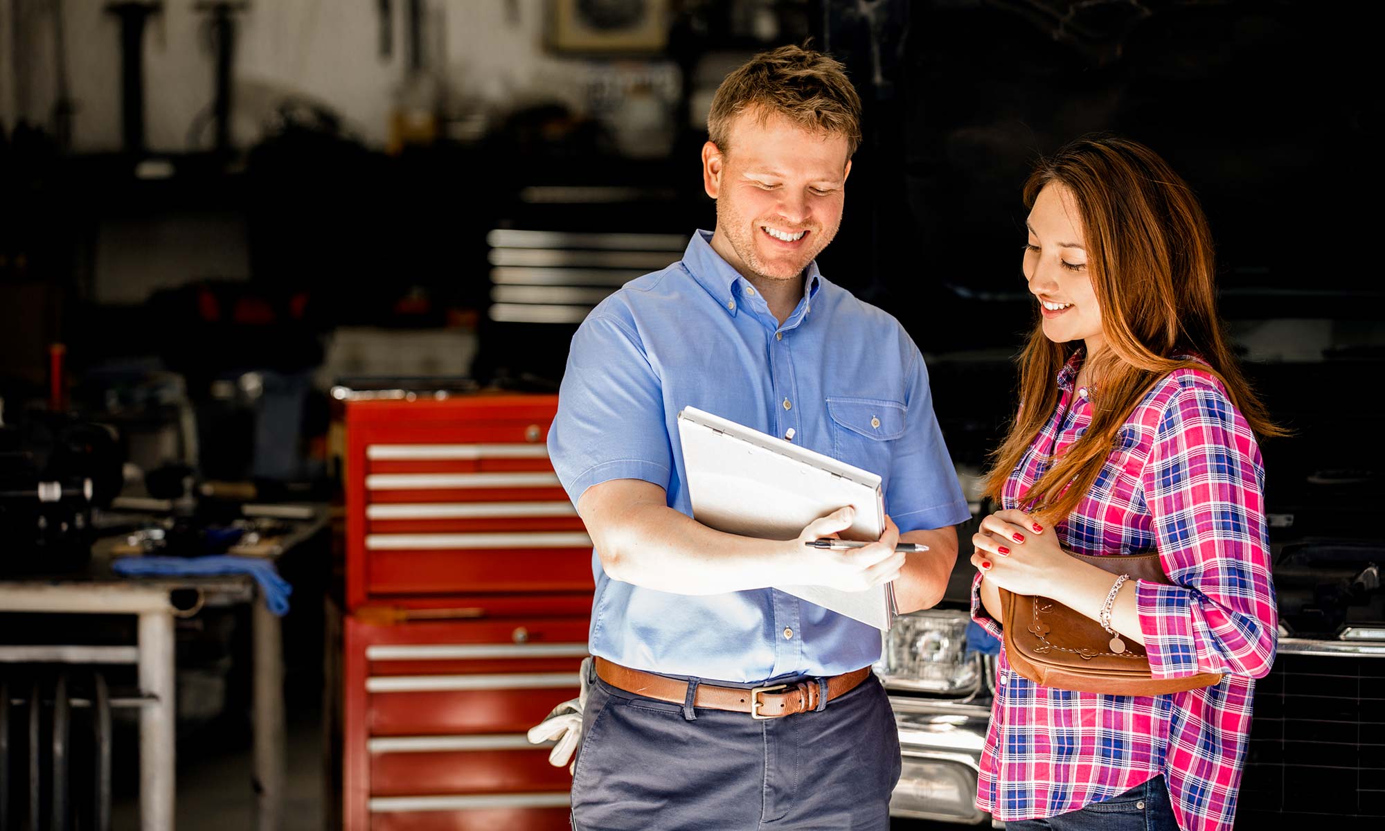 A male auto mechanic discusses a contract with a female customer.