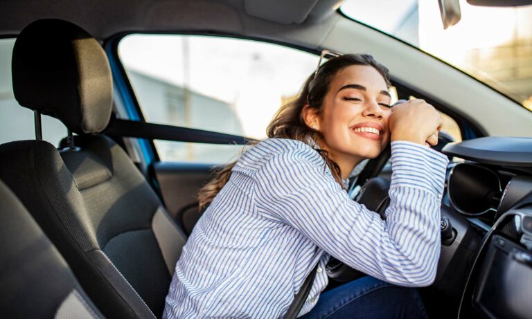 Image of happy woman leaning on her steering wheel