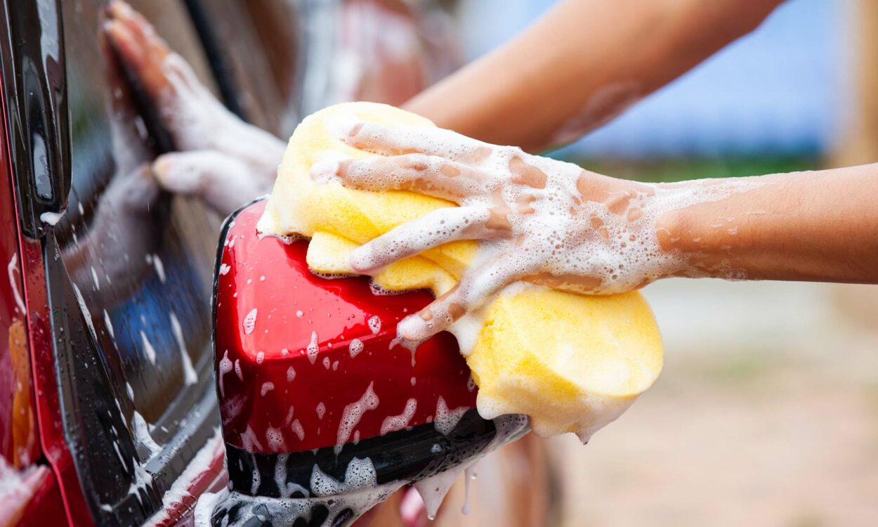 A close up image of a person washing a red car