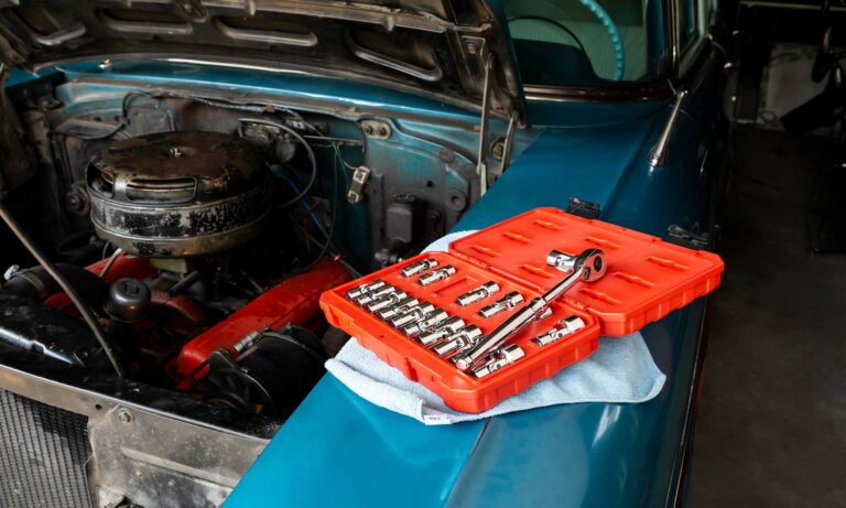 An open toolbox sits next to a car engine.