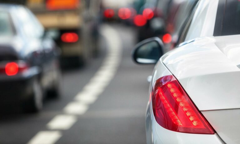 An up-close image of a white car stuck in traffic.