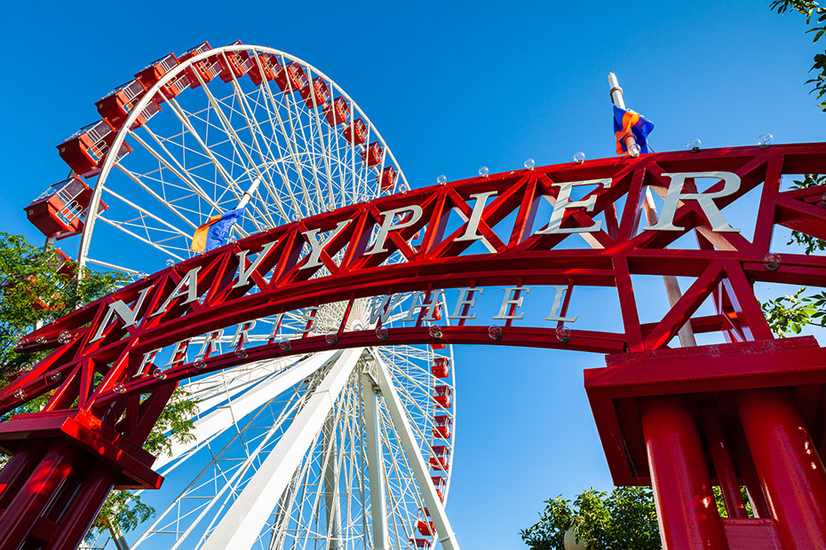 The sign for Navy Pier in Chicago in front of a Ferris wheel.