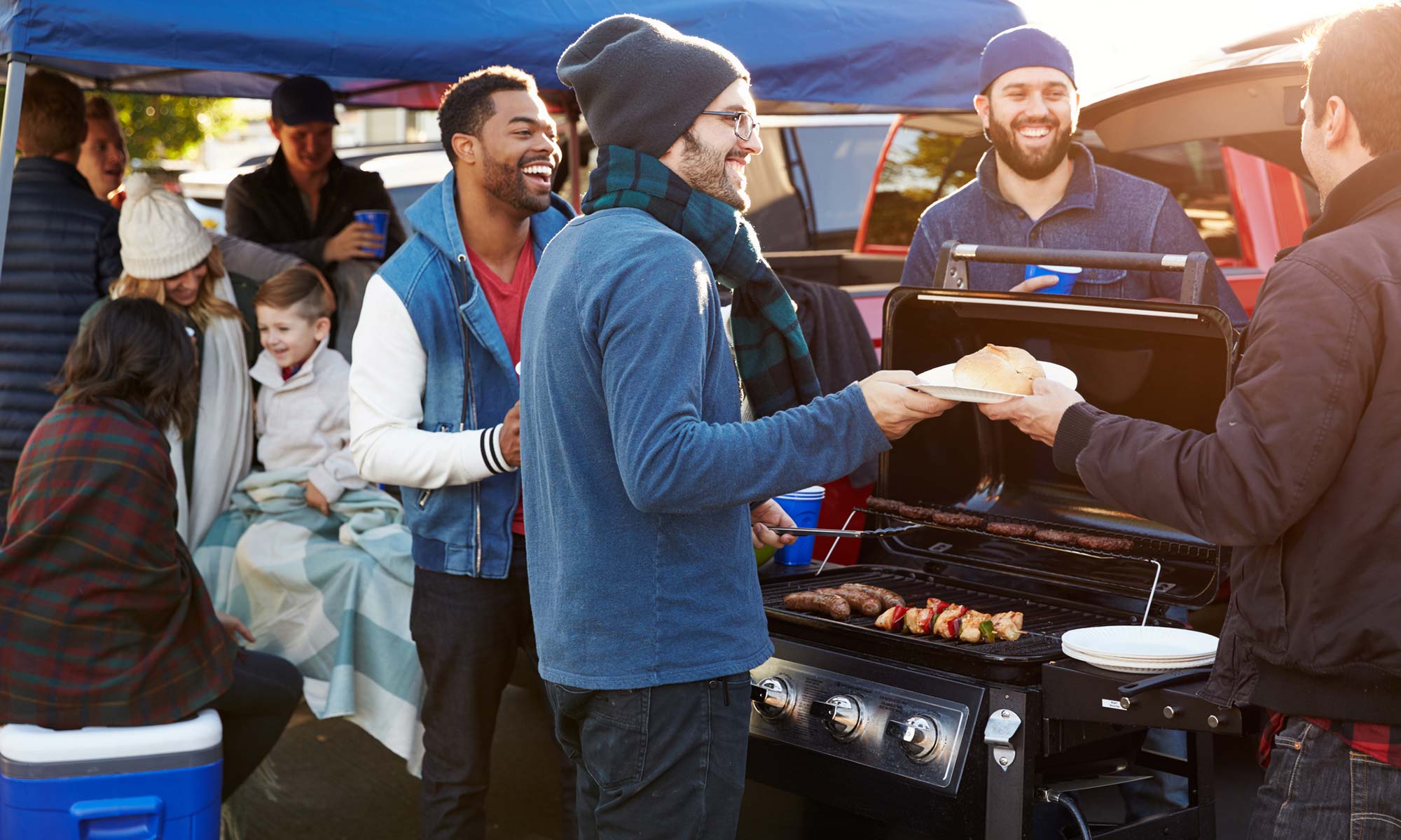 A group of people enjoying a tailgate party in the Fall.