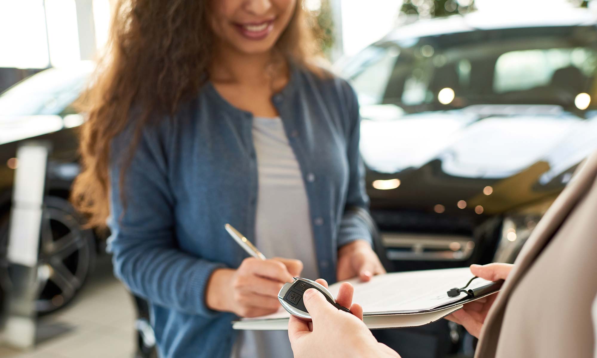 A young woman signing a contract to purchase a car.