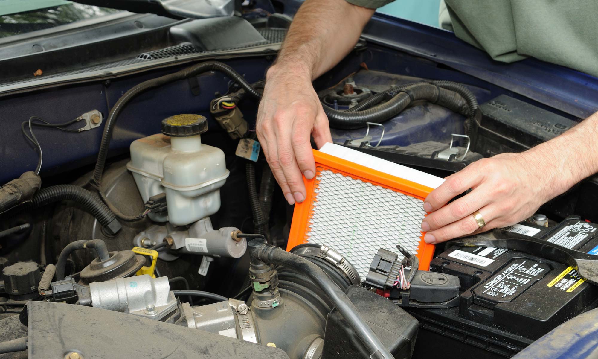 A mechanic changing a car's engine air filter.