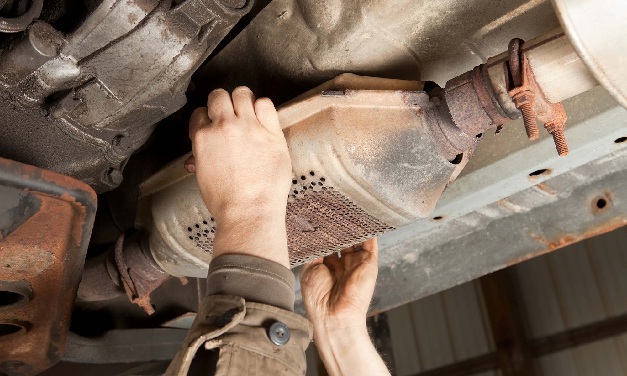 A mechanic fixing a catalytic converter.