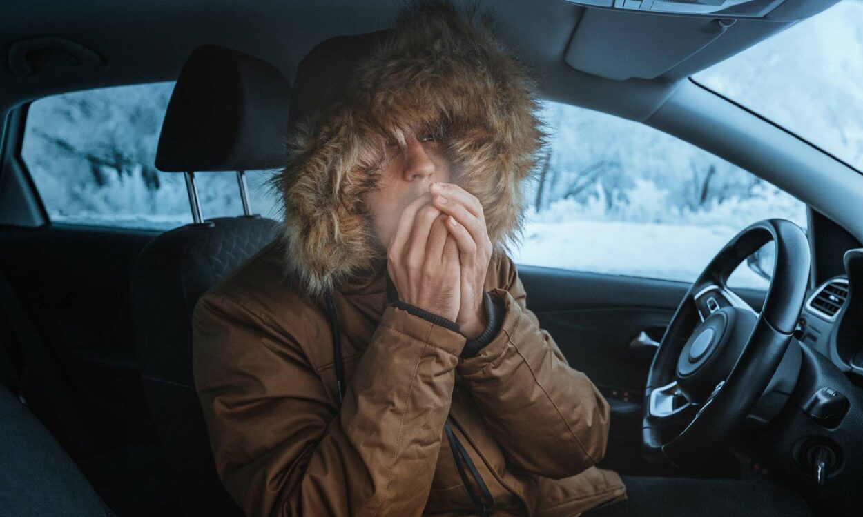 A young man sitting in his car with a broken heater.