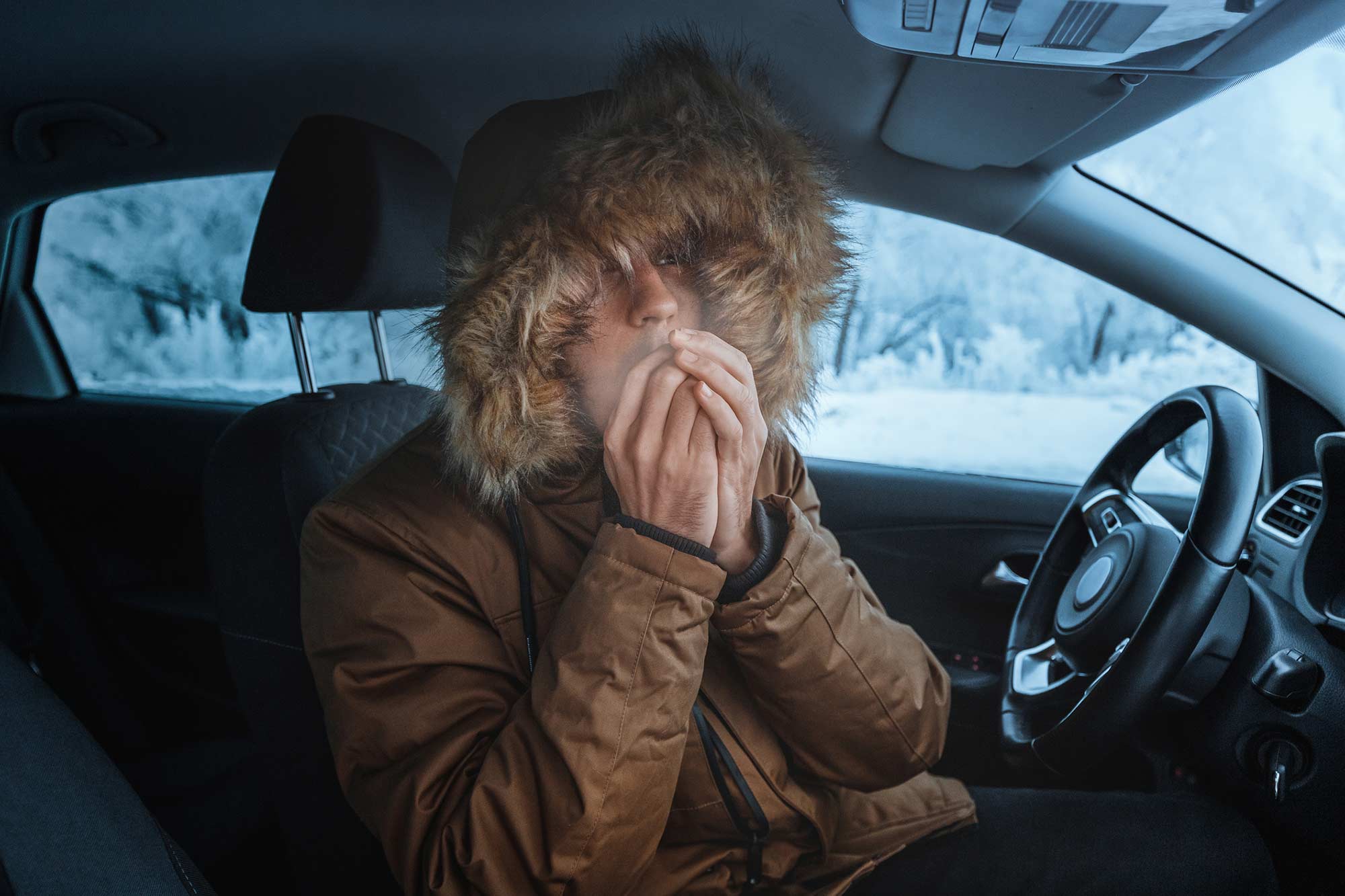 A young man sitting in his car with a broken heater.