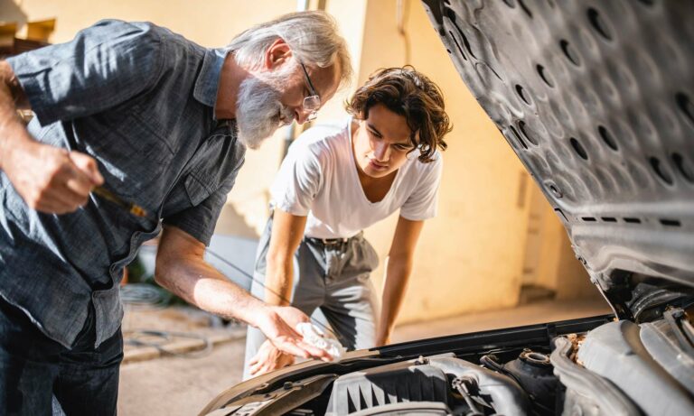 A grandfather and grandson working on a vehicle at home.