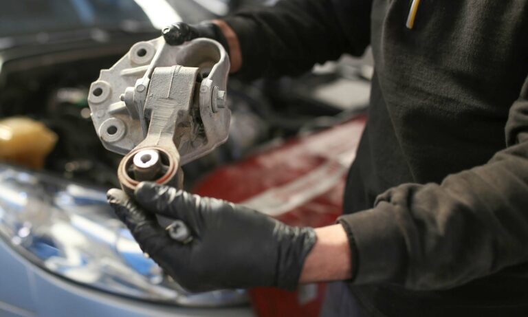 A car mechanic replacing an engine mount.