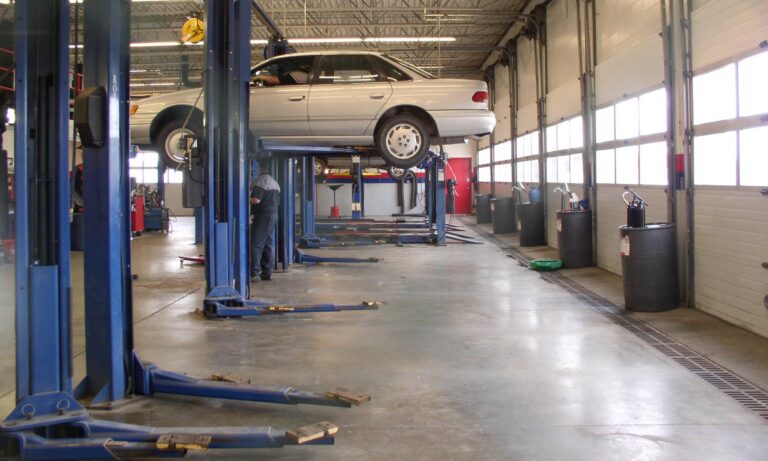 A mechanic working underneath a vehicle that is raised on a lift.